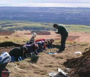 Discover the Ancient Lomonds! Young volunteers take part in the dig with views of Glenrothes behind.